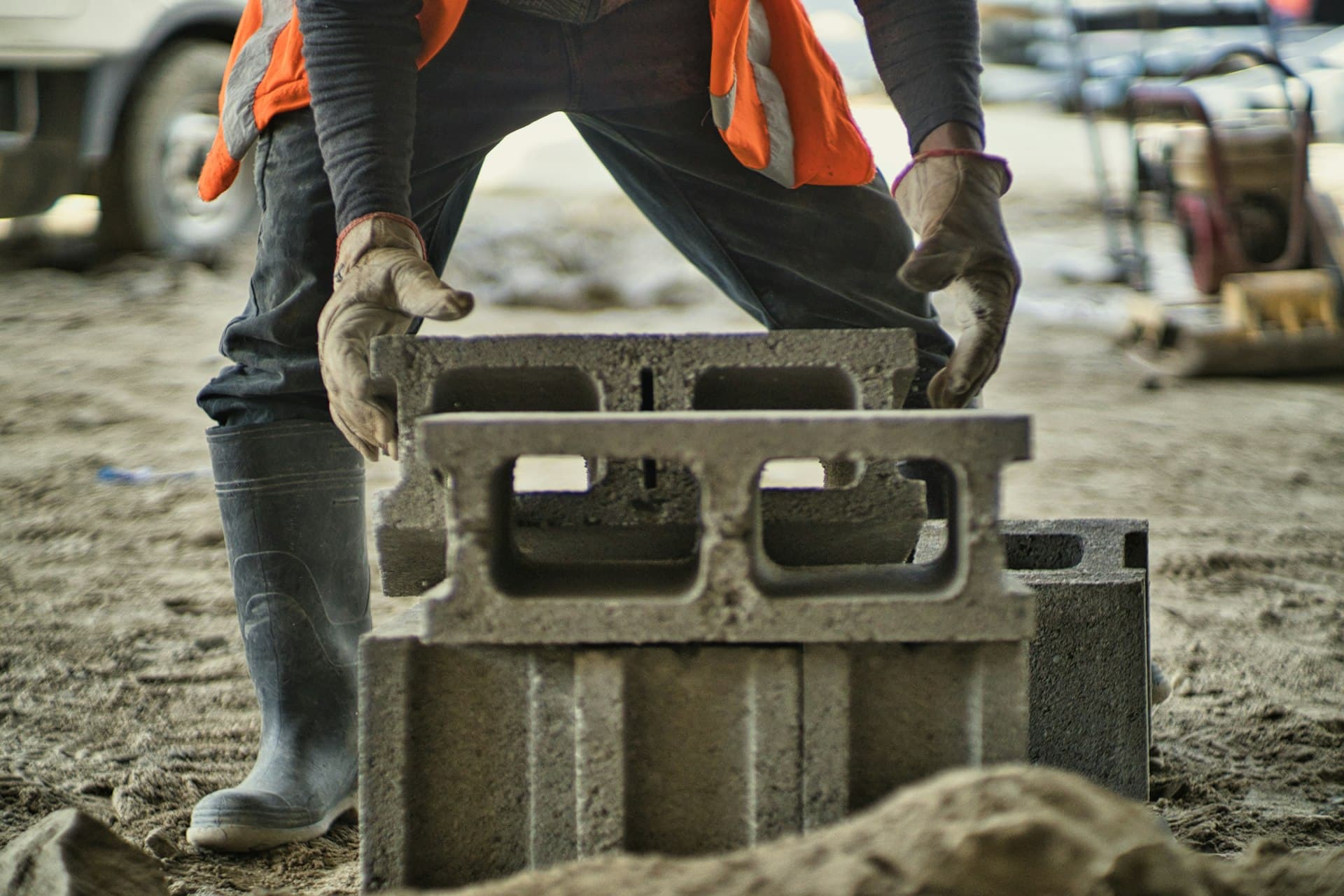 Operaio con dispositivi di sicurezza posiziona blocchi di calcestruzzo in cantiere